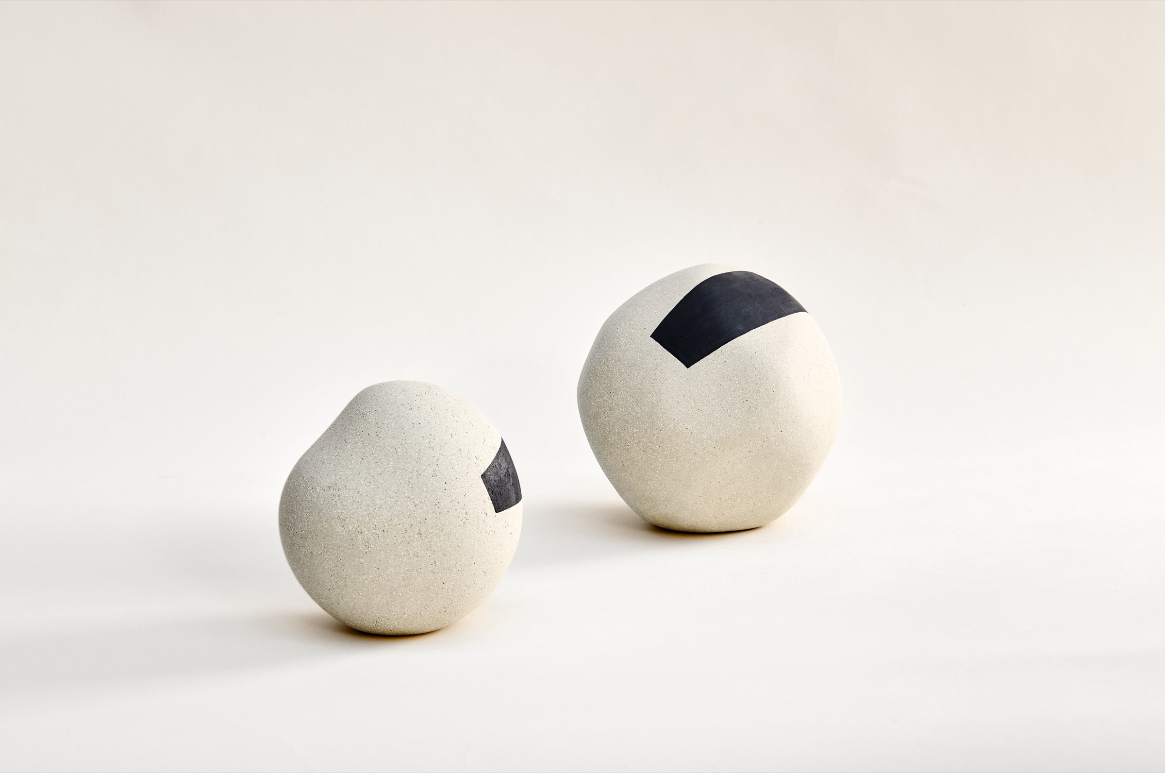 Deux sculptures Ishi sphériques en porcelaine et grès, décor d'oxydes bleu nuit, surface mate et granuleuse
