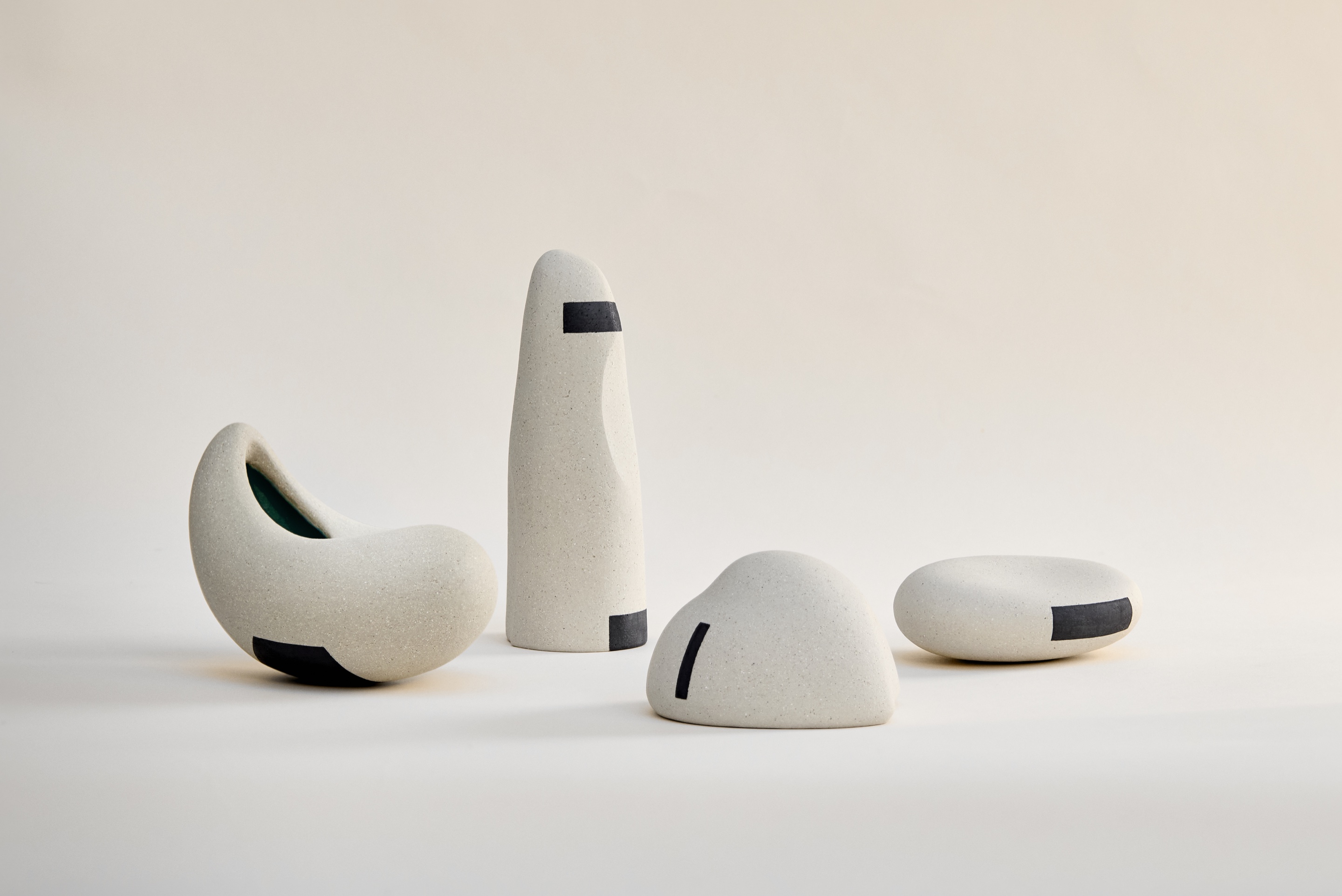 Ensemble de quatre sculptures Ishi en porcelaine et grès non émaillés, décor géométrique d'oxydes, forme ouverte laissant voir un émail bleu intérieur texturé comme l'eau
