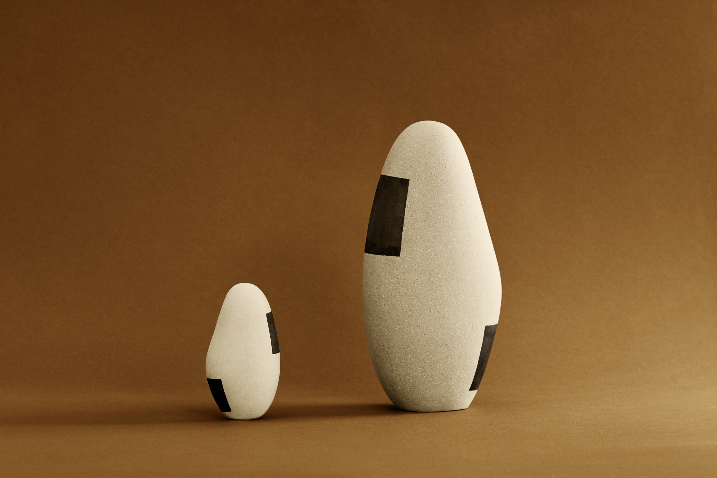 Duo de sculptures Ishi de tailles contrastées : deux ovoïdes en grès non émaillé, décor géométrique noir
