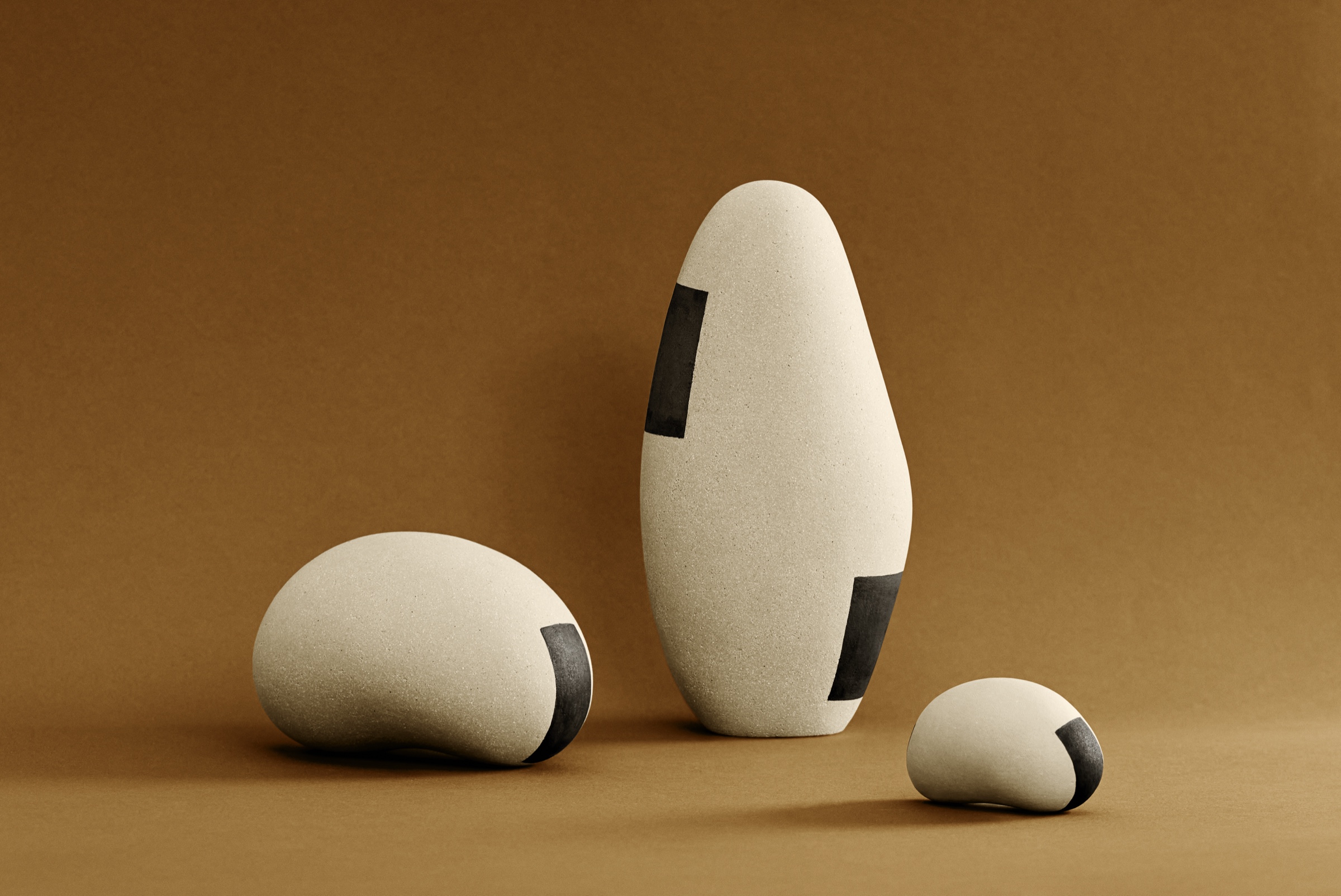 Trois sculptures Ishi en porcelaine et grès : grand ovoïde vertical et deux galets, surface non émaillée, bandes d'oxydes noirs